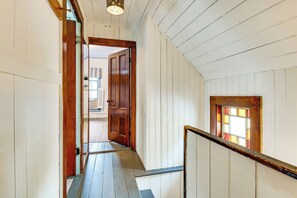 Een houten trap met een leuning, leidend naar een kamer met een raam.