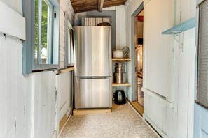 A narrow hallway with a stainless steel refrigerator and a wooden shelf unit. - Tiny Antique Cottage - 2 Minutes From Short Sands! (York)