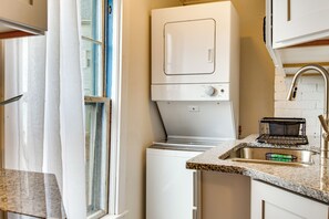 A compact kitchen with a built-in washer and dryer, a granite countertop, and a stainless steel sink.