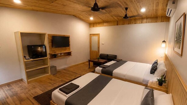 Une chambre avec deux lits, une télévision, un bureau et un ventilateur de plafond.
