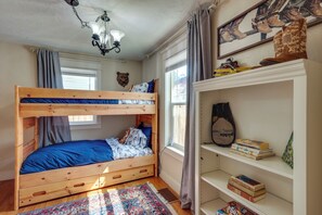 A bunk bed with a blue mattress, a wooden headboard, and a patterned rug.