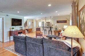 A living room with a sofa, chairs, a desk, a television, and a lamp.