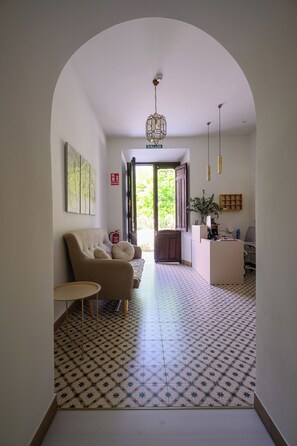 A living room with a sofa, a small table, a desk with a computer, and a patterned floor. - Deluxe Apartment with Garden View / Bright, spacious, and comfortable (Salobreña)