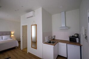 A compact hotel room with a bed, a small kitchenette, and a mirror. - Deluxe Apartment with Garden View / Bright, spacious, and comfortable (Salobreña)