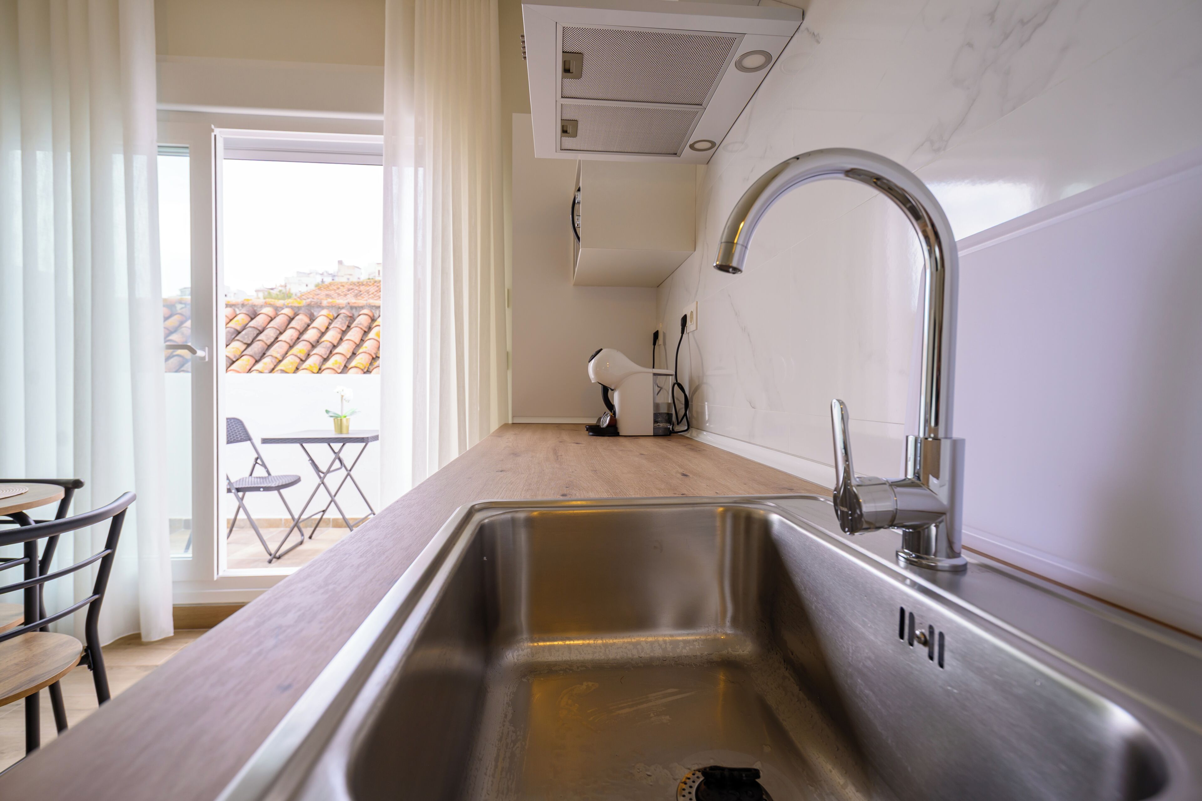 A kitchen with a stainless steel sink, a modern faucet, and a wooden countertop.