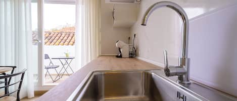 A kitchen with a stainless steel sink, a modern faucet, and a wooden countertop.