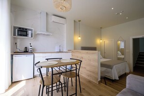 Ein kompakter Wohnraum mit Küchenzeile, Essbereich und Bett.