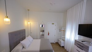 A hotel room with a bed, bedside table, TV, wardrobe, and a mirror. - Luxury Studio with a Terrace and Views of the Alcazaba (Salobreña)