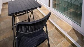 A balcony with a table and chairs, a sliding glass door, and a wall-mounted light fixture. - Luxury Studio with a Terrace and Views of the Alcazaba (Salobreña)