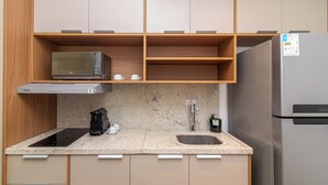 Moderni keittiö, jossa on mikroaaltouuni, kahvinkeitin ja ruostumattomasta teräksestä valmistettu jääkaappi.