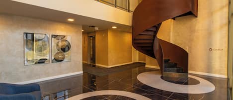 A modern interior with a spiral staircase, a glass elevator, and abstract wall art.