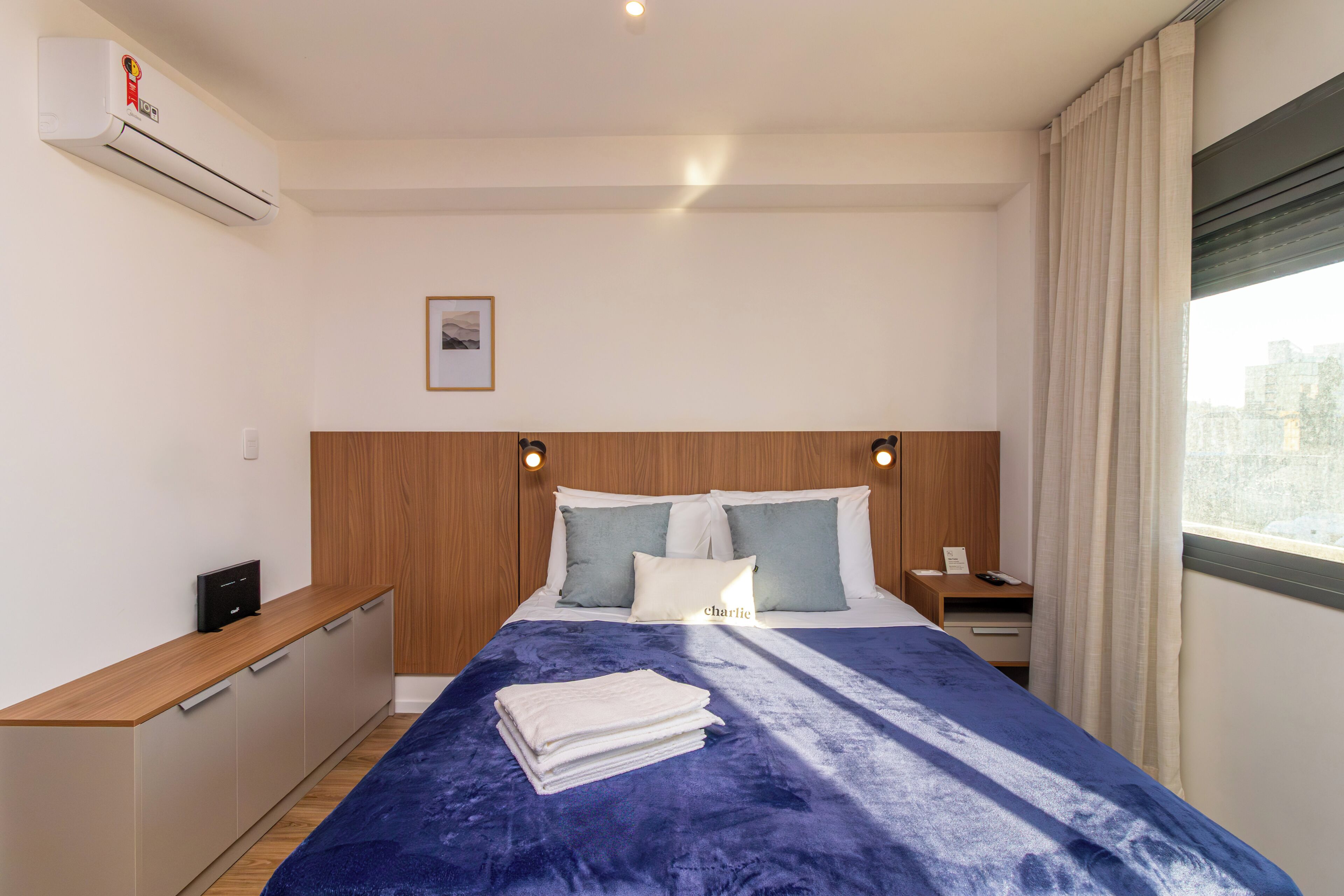 Une chambre d’hôtel avec un lit, des tables de chevet, un bureau et une fenêtre avec des rideaux.