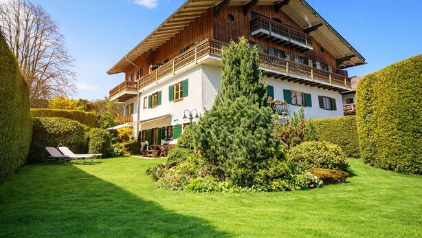 Ein zweigeschossiges Gebäude mit Balkon und gepflegtem Rasen.
