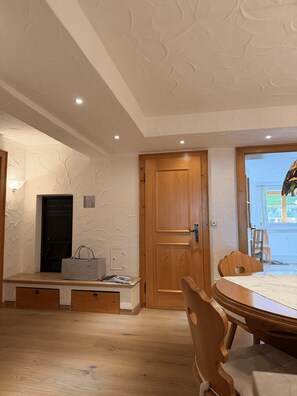 A room with a wooden door, a table with chairs, a bench with a handbag, and a wall with a textured pattern. - Relax in style in the heart of Bad Wiessee. Welcome to your getaway! (Bad Wiessee)