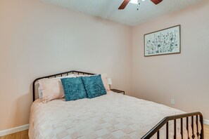 A bedroom with a bed, a ceiling fan, a nightstand, and a wall-mounted artwork. - Suburban Family Home Between Dallas & Arlington (Grand Prairie)