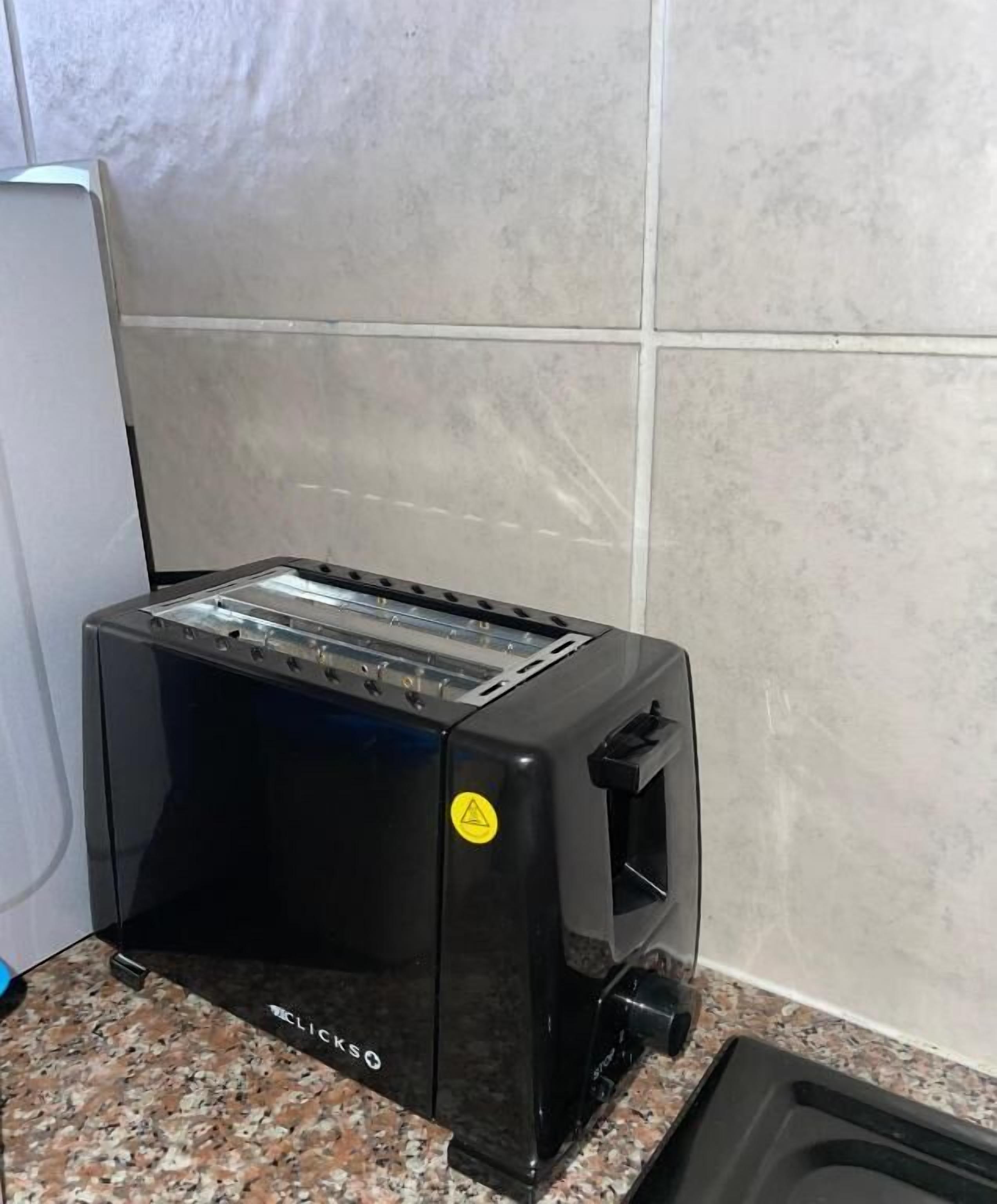 A black toaster on a granite countertop with a tiled wall in the background.