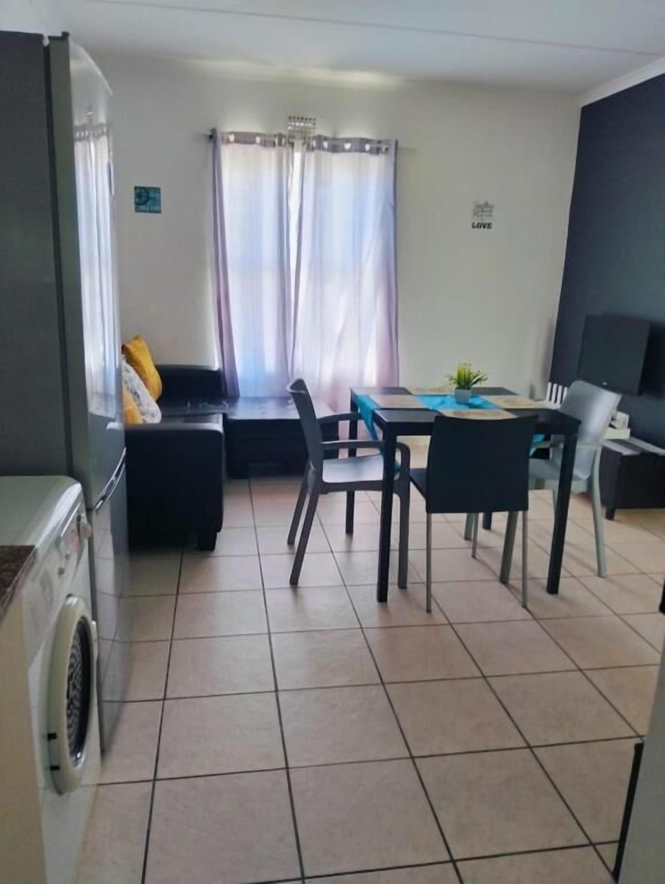 A compact living space with a dining area, a sofa, a washing machine, and a television.