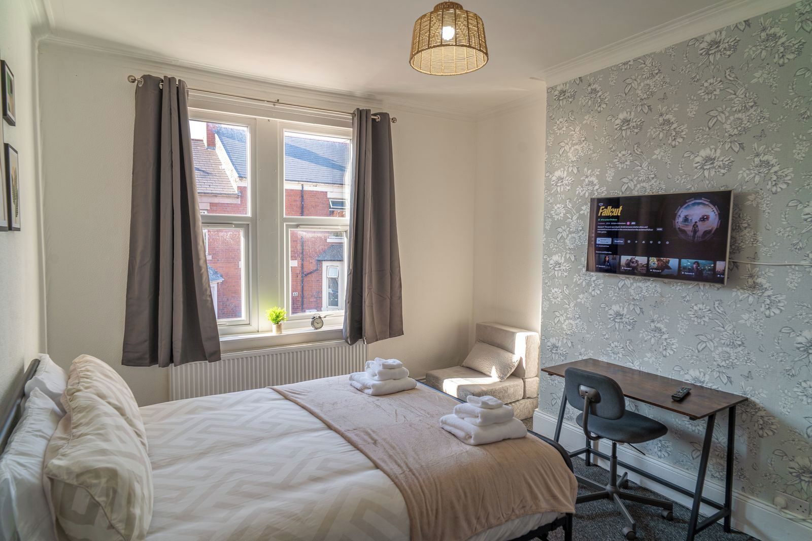Une chambre d’hôtel équipée d’un lit, d’un bureau, d’une chaise, d’une télévision et d’une fenêtre avec des rideaux.