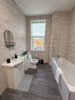 Een moderne badkamer met toilet, wastafel en bad.