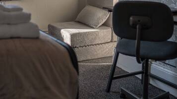 A hotel room with a bed, a chair, a small table, and a television.