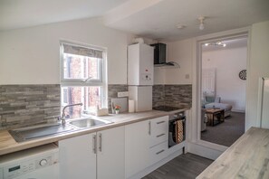A compact kitchen with a built-in dishwasher, a stove, and a refrigerator. - Family & Contractor Stay | Sleeps 6 | Free Parking (Gateshead)
