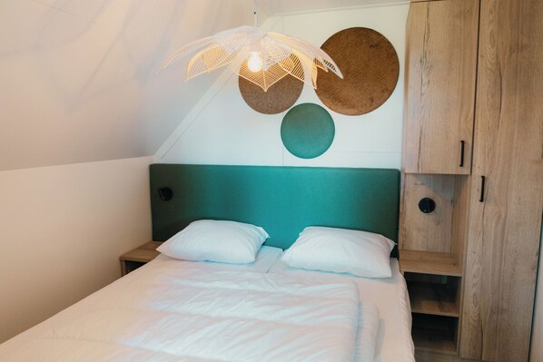 Ein Schlafzimmer mit einem Bett, einem Holzschrank und einer Wandleuchte.