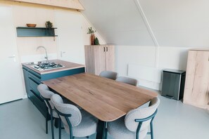 Eine moderne Küche mit Holztisch und -stühlen, einem eingebauten Herd und einem kleinen Spülbecken.