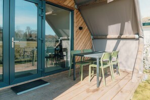 Ein moderner Außenbereich mit Sitzgelegenheiten, Tisch und Stühlen, einer Schiebetür und einer Holzterrasse.