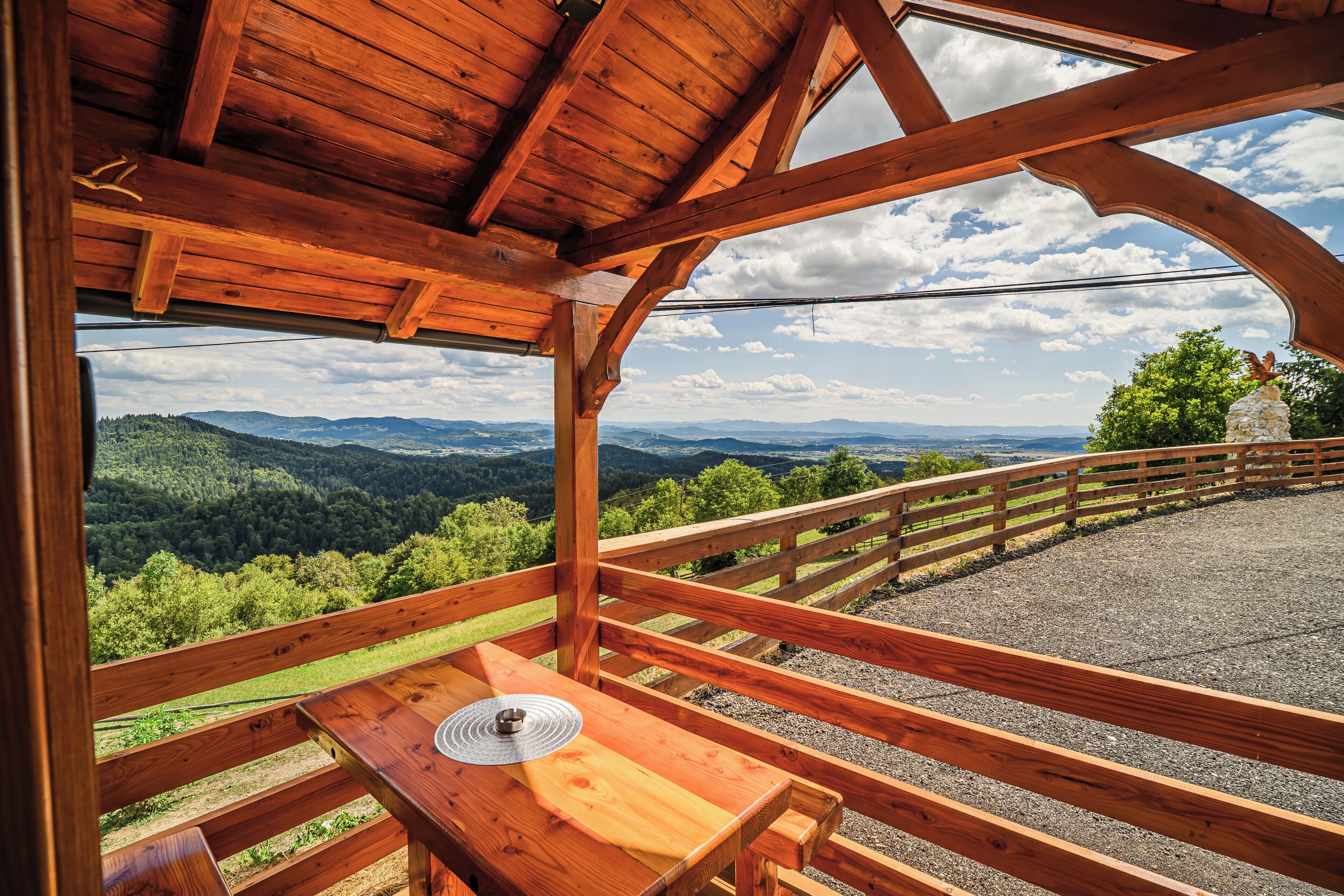 Une terrasse en bois avec une table et un banc, offrant une vue sur un paysage montagneux.