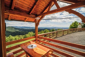 A wooden deck with a table and bench, overlooking a mountainous landscape. - Tiny Panorama Cottages (Kamnik)