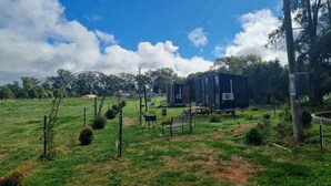 A rural property with a small house, a fenced yard, and a clear sky. - The Druids Rest by Tiny Away (Curlwaa)