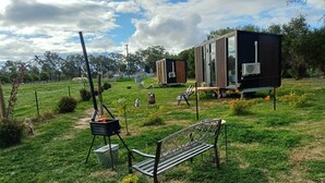 A modern outdoor living area with a grill, a bench, and a small building structure. - The Druids Rest by Tiny Away (Curlwaa)