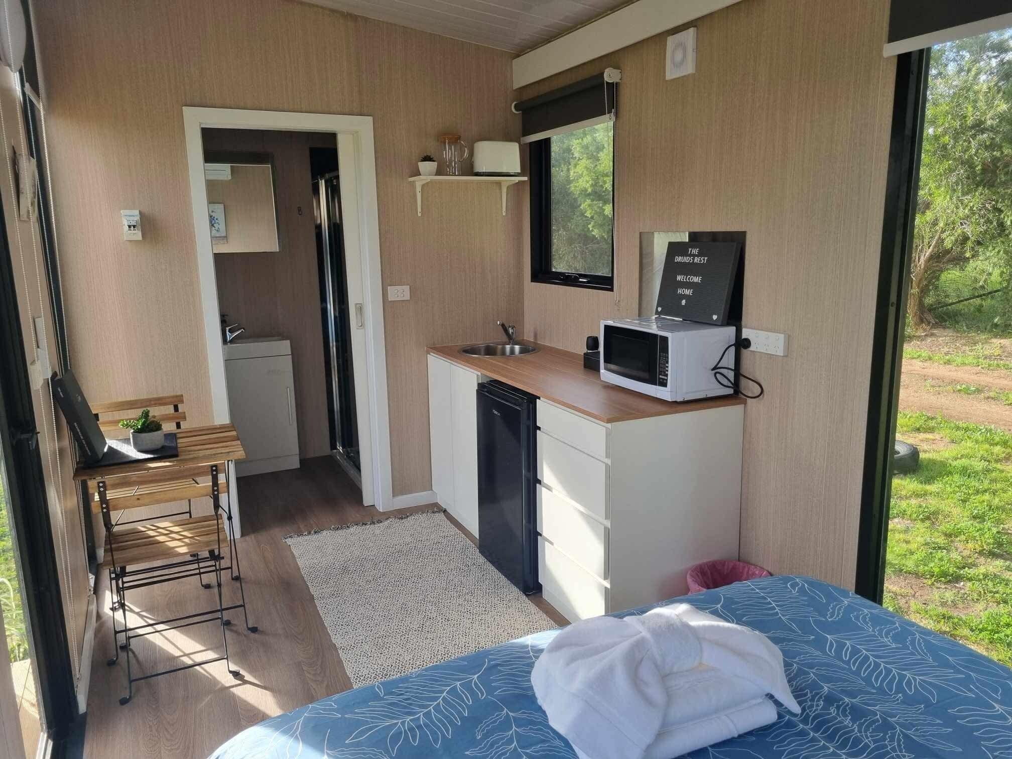 A compact room with a bed, a small kitchenette, a window, and a view of the outdoors.
