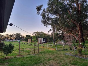 A fenced outdoor area with a large tree, a small building, and a utility pole.