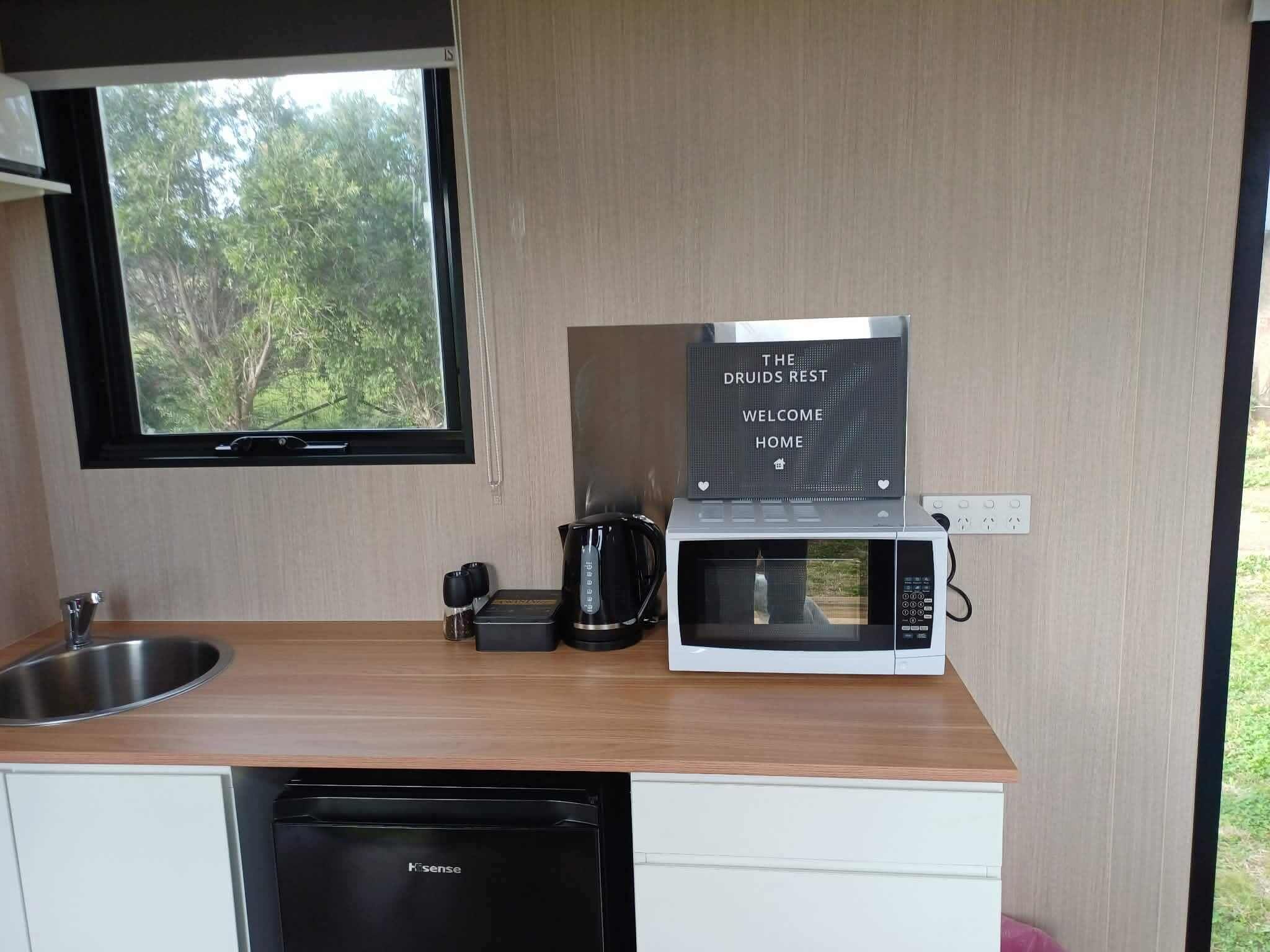 A compact kitchenette with a window, a coffee maker, a microwave, and a dishwasher.