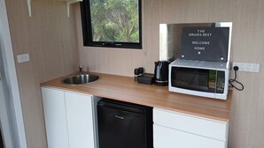 A compact kitchenette with a sink, a microwave, and a small window. - The Druids Rest by Tiny Away (Curlwaa)