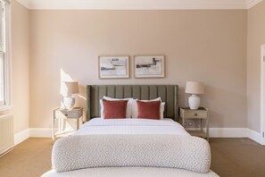 A hotel room with a large bed, two bedside tables, a headboard, and two framed pictures on the wall. - The Steele Blue House (London)