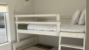 Un lit superposé à trois niveaux, un luminaire suspendu et une fenêtre avec vue.