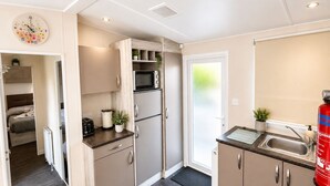 A compact kitchen with a microwave, refrigerator, and a sink. - Aldous Rest - Cosy Park Home in quiet Norfolk Countryside (Fritton)