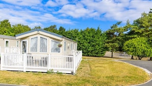 A mobile home with a porch and a fenced yard.