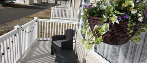 A covered outdoor area with wicker furniture and a hanging flower basket.