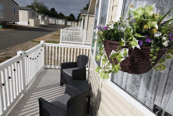 A covered outdoor area with wicker furniture and a hanging flower basket.