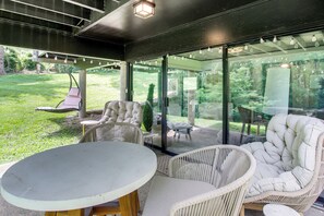 An outdoor patio with wicker furniture, a table, and a swing chair. - Award-Winning Mr Mid-Modern-Century (Iowa City)