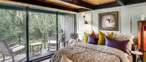 A bedroom with a large bed, a view of the outdoors, and a balcony with furniture.