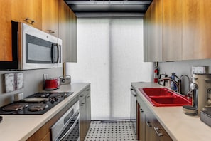 A compact kitchen with a microwave, stove, and sink. - Award-Winning Mr Mid-Modern-Century (Iowa City)