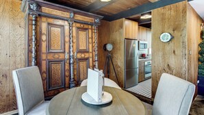 A room with a wooden door, a round table with chairs, a modern kitchen with appliances, and a clock on the wall. - Award-Winning Mr Mid-Modern-Century (Iowa City)