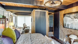 A room with a bed, a wooden ceiling, a chandelier, and a door leading to another room. - Award-Winning Mr Mid-Modern-Century (Iowa City)