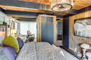 A room with a bed, a wooden ceiling, a chandelier, and a door leading to another room. - Award-Winning Mr Mid-Modern-Century (Iowa City)
