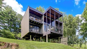 A modern two-story building with a balcony on the upper level, surrounded by greenery. - Award-Winning Mr Mid-Modern-Century (Iowa City)
