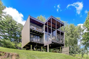 A modern two-story building with a balcony on the upper level, surrounded by greenery. - Award-Winning Mr Mid-Modern-Century (Iowa City)